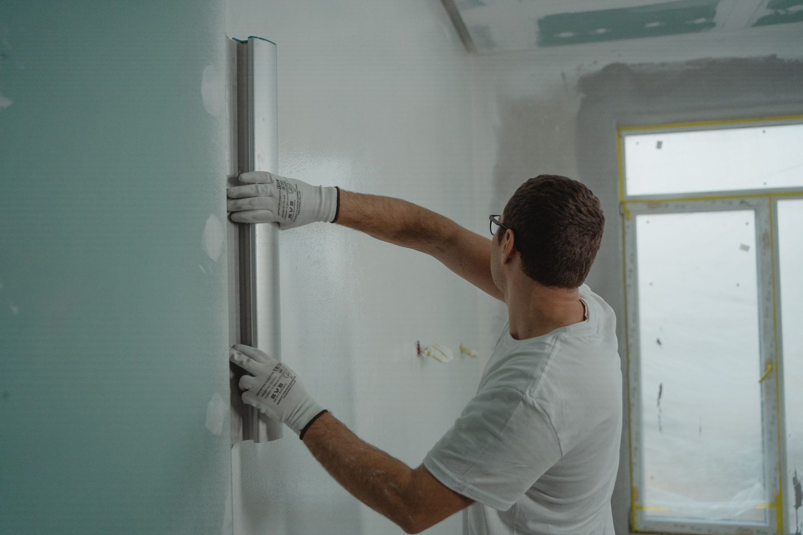 Plasterer flattening a freshly plastered wall