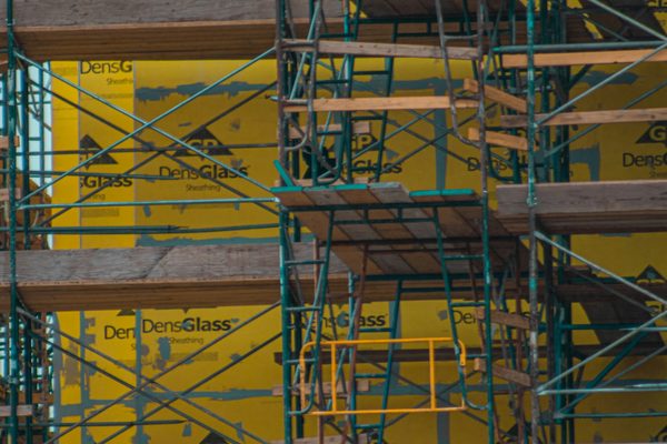 Building envelope with sheathing boards behind railed scaffold